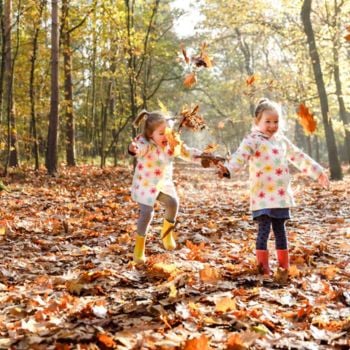 Kinder spielen mit Herbstblättern