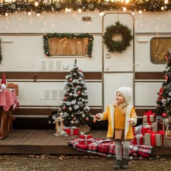 Meisje op een slee met een kerstboom en chocolademelk